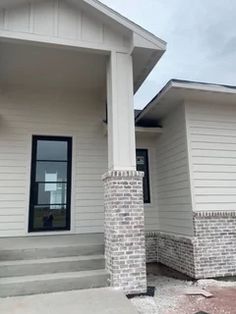 a white house with two windows and steps leading up to the front door on a cloudy day