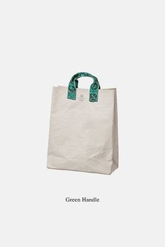 a white bag with green handles on the front and bottom, sitting against a white background