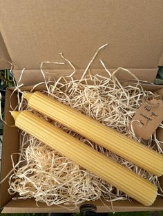 two uncooked pasta sticks in a cardboard box with some string attached to it