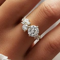 a woman's hand with a diamond ring on top of her finger and two diamonds in the middle