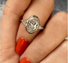 a woman's hand with an orange manicured nail polish and a diamond ring