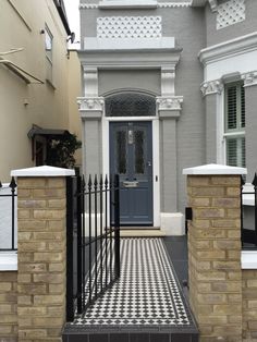 a black and white checkered floor in front of a gray house with a blue door