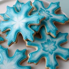 decorated cookies on a white plate with blue frosting and snowflakes in the background