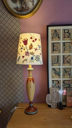 a lamp sitting on top of a wooden table next to a framed photograph and a clock