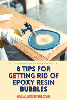 a person in white gloves painting a table with blue paint and the words 8 tips for getting rid of epoxy resin bubbles