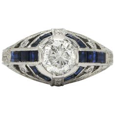 An intriguing revivalist Art Deco diamond engagement ring. A blazing, brilliant 1.02 carat solitaire sits regally in a sapphire kissed stepped pyramid dome. You will adore the old world milgrain and engraved band details. Judged as H, near colorless. Expertly hand fabricated in 18kt white gold, a faithful emulation of a 1920s classic, using the same tools and techniques from 100 years ago. The workmanship rivals Cartier, Tiffany, Van Cleef & Arpels.   Condition: New Era: Art Deco Year: 2016 Meta Estate Engagement Ring, Art Deco Diamond Ring Engagement, Milgrain Engagement Ring, 1 Carat Engagement Rings, Sapphire Diamond Engagement, Blue Engagement Ring, Sapphire Engagement Ring Blue, French Provincial, Antique Engagement Rings