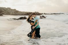 a man and woman are hugging in the water at the beach while holding each other