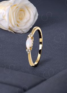 a white rose sitting on top of a table next to a gold ring with diamonds