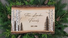 a wooden plaque with pine cones and evergreens on it that says the lodge family