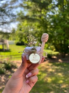 a person holding a jar with flowers and a wooden stick in it that says happy birthday