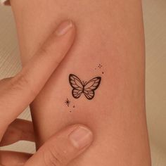 a small butterfly tattoo on the back of a woman's left arm