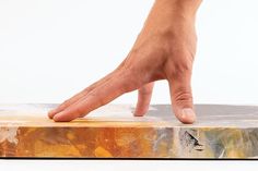 a person's hand reaching for something on top of a piece of art that has been painted