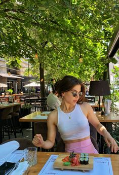 A brunette girl sitting outside in a sushi restaurant. Her hair is clipped back and she is wearing Ray Ban sunglasses, a white tank top and pink pants Sushi Restaurant, Wellness Blog, Kim K, Fashion Streetwear, Beauty Wellness, Body Positivity, Fashion Fashion, Fashion Beauty, Women's Fashion