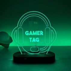 a neon sign that says gamer tag with headphones on it in front of a green background