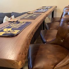 a long wooden table with two chairs next to it and a couch in the background