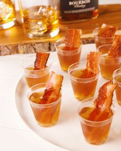 small cups filled with different types of food on a white plate next to a bottle