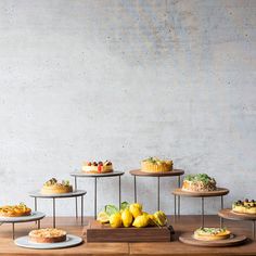 an assortment of cakes and pastries on wooden serving trays in front of a concrete wall