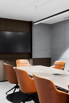 an empty conference room with orange chairs and a flat screen tv mounted on the wall