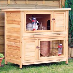 an outdoor rabbit hut with two rabbits in it's doors and one on the outside