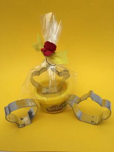 a yellow table topped with three plastic objects and a red rose sitting on top of it