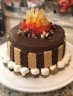 a chocolate cake topped with gummy bears and marshmallows on a white plate