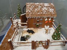 a gingerbread house with snow on the roof and decorations around it, including cats