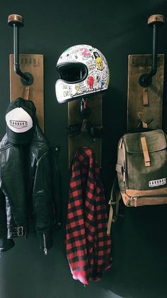 a motorcycle helmet and other items are hanging on the wall next to two wooden pegs