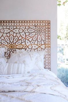 an image of a bed with white sheets and pillows on it's headboard