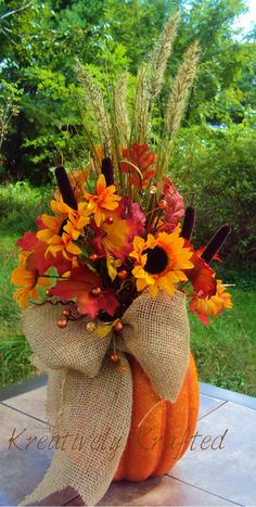 a pumpkin decorated with fall flowers on a table