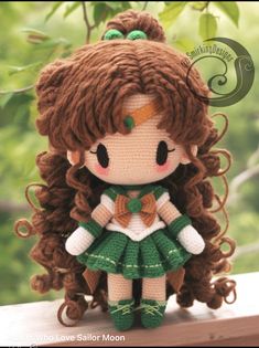 a crocheted doll with long brown hair and green dress sitting on a ledge