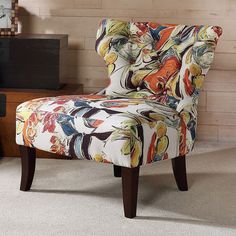 an upholstered chair in a living room with a clock on the wall behind it