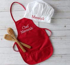 two personalized aprons with wooden utensils on a white wood table top