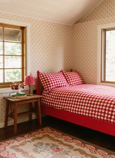 a red and white checkered bedspread in a small room with two windows