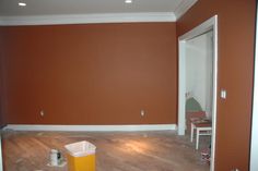 an empty room with orange walls and white trim on the walls is being painted brown