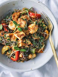 a white bowl filled with vegetables and meat on top of a table next to a fork