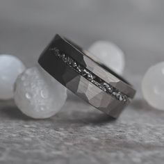 two wedding bands with diamonds on them sitting in front of some white rocks and bubbles