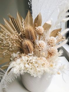 a white vase filled with lots of different types of flowers on top of a table