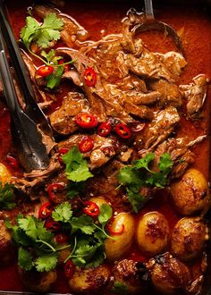 a pan filled with meat, potatoes and cilantro