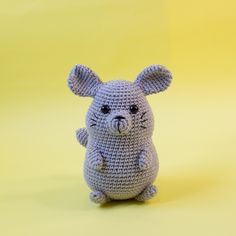 a small crocheted animal sitting on top of a yellow surface with one eye open