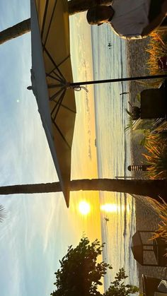 the sun is setting over the beach with umbrellas