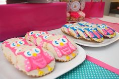 decorated cookies on plates sitting on a table with pink and blue decorations in the background