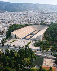 an aerial view of a stadium in the middle of a city with mountains in the background