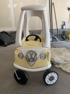 a yellow and white toy car sitting on top of a cement floor in a garage