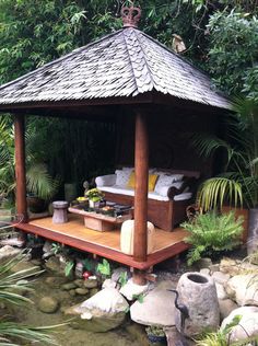 a wooden gazebo sitting in the middle of a lush green forest