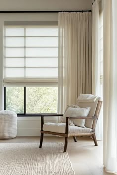 a chair and ottoman in front of a window with white drapes on the windowsill