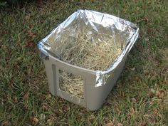 a plastic container filled with hay sitting in the grass