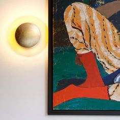 a painting is hanging on the wall next to a light that has a button in front of it