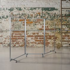 an empty room with a brick wall and two metal bars in the foreground, against a backdrop of rusted bricks