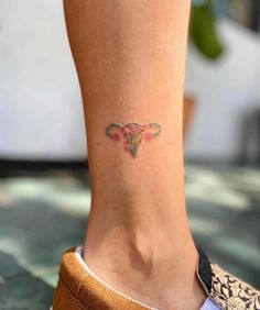 a woman's foot with a small tattoo on the side of her leg and pink flowers