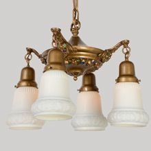 an antique brass chandelier with five white glass shades hanging from it's ceiling